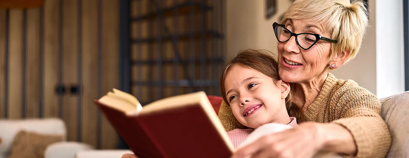 Grandma reads to her granddaughter from the book.